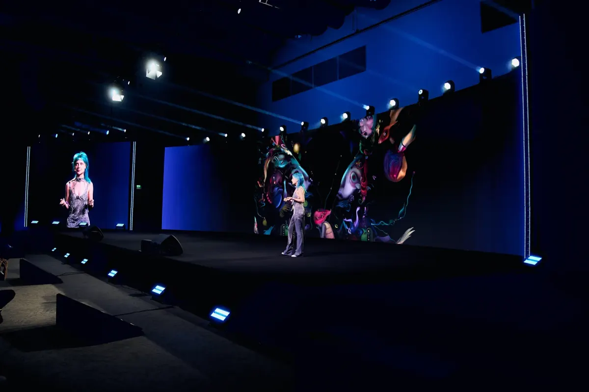 Presenter on a lit event stage with a large backdrop at a conference or MICE production in Dubai Presenter on a lit event stage with a large backdrop at a conference or MICE production in Dubai