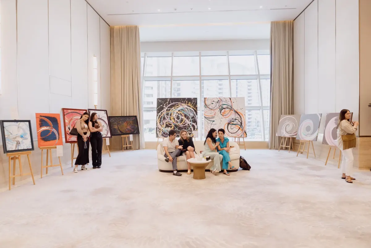 Indoor event space with guests seated beside paintings on easels in Dubai